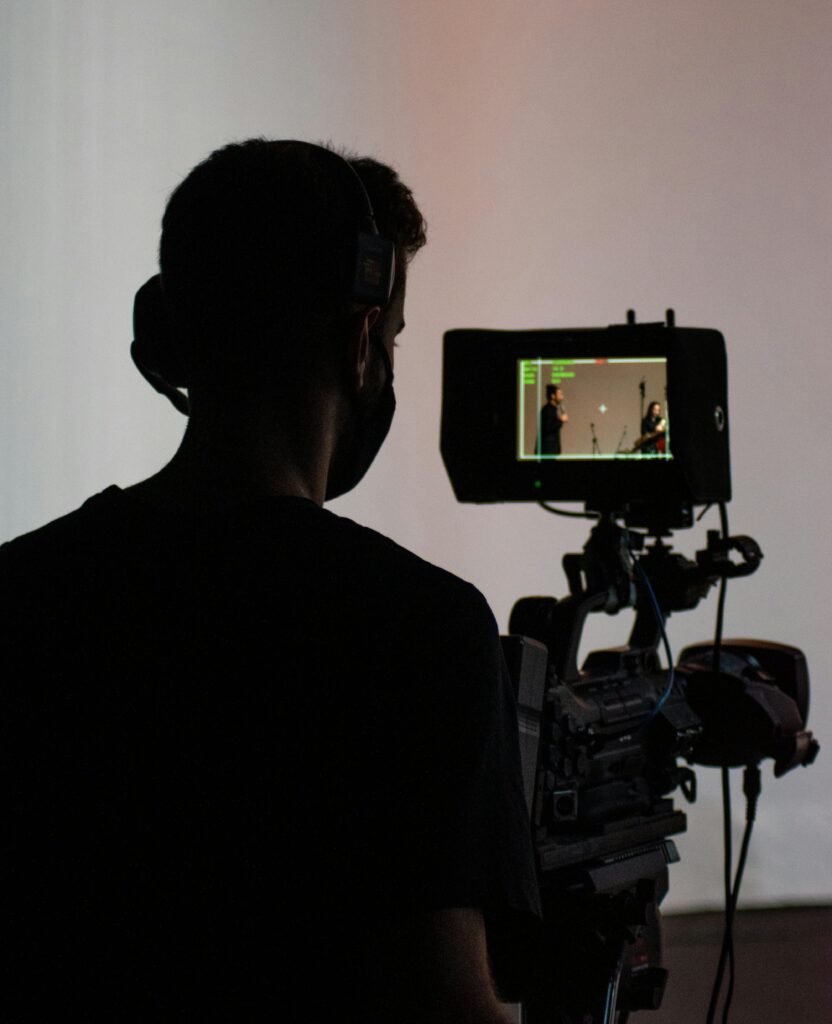 Silhouette of a cameraman operating professional video equipment in a studio setting.